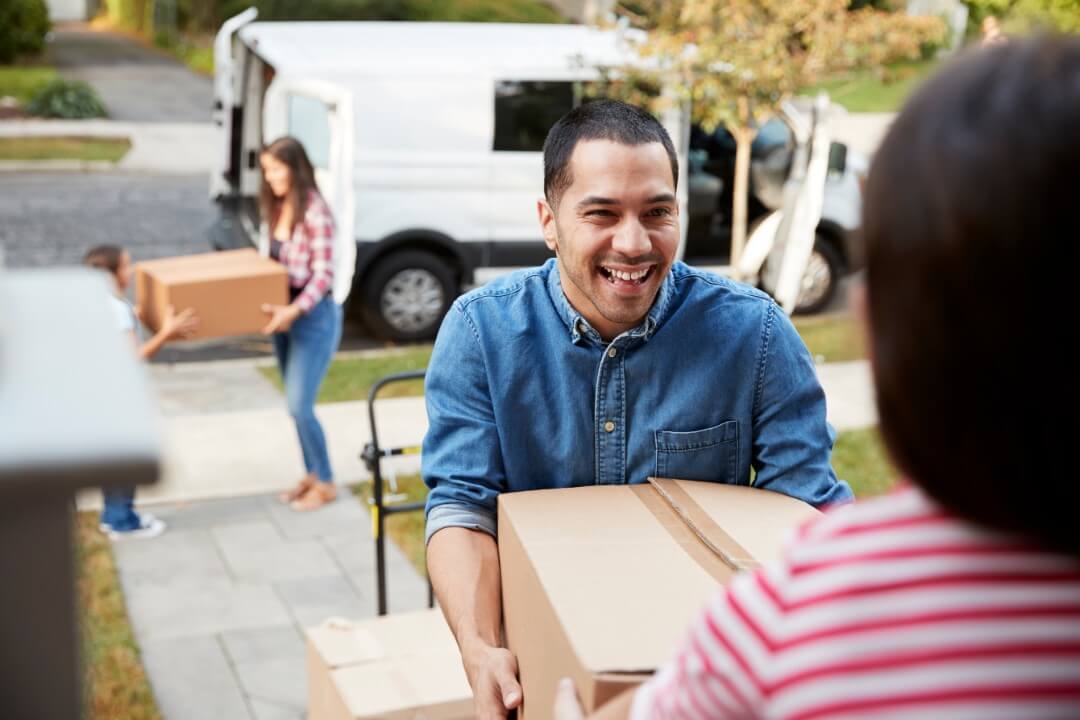 family smiling while moving boxes