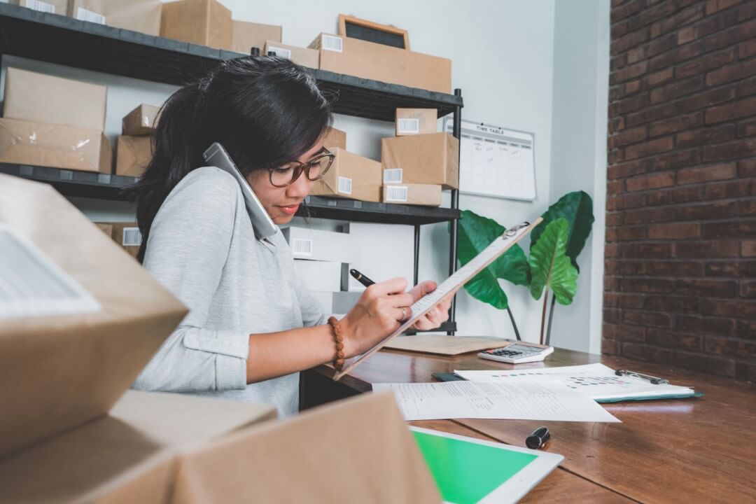 woman note taking while on the phone