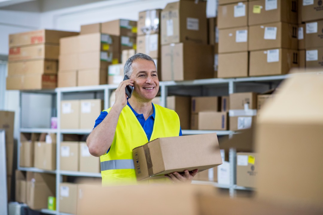 man on the phone smiling while holding box